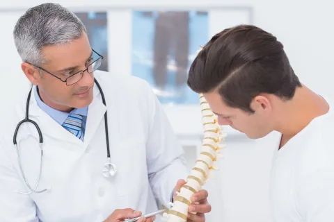 Arzt erläutert einem Mann mit Rückenschmerzen, worauf es bei der Rückengesundheit ankommmt- © Shutterstock, wavebreakmedia