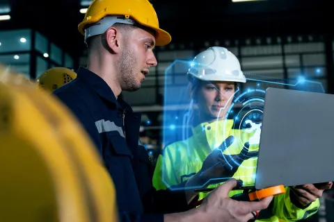 Zwei Mitarbeiter in Schutzkleidung unterhalten sich über die Maßnahmen, die die KI zum Arbeitsschutz vorgeschlagen hat. © Adobe Stock, Kannapat