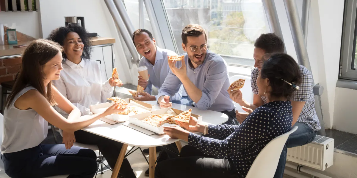 Mitarbeiter essen in der Pause Pizza und müssen mit einem Mitagstief aufgrund des fettigen Essens rechnen. © Shutterstock, fizkes