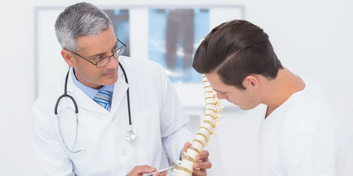 Arzt erläutert einem Mann mit Rückenschmerzen, worauf es bei der Rückengesundheit ankommmt- © Shutterstock, wavebreakmedia