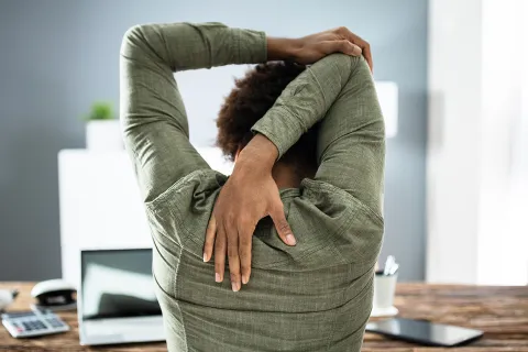 Mitarbeiterin leidet an Verspannung, da sie viel am PC arbeitet. © Shutterstock, Andrey_Popov