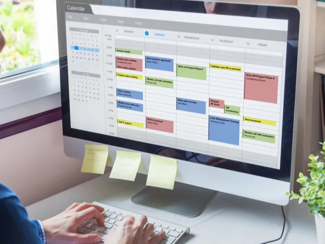 Mitarbeiter im Homeoffice hat digitalen Kalender geöffnet und Notizzettel kleben am Bildschirm. © Shutterstock, NicoElNino