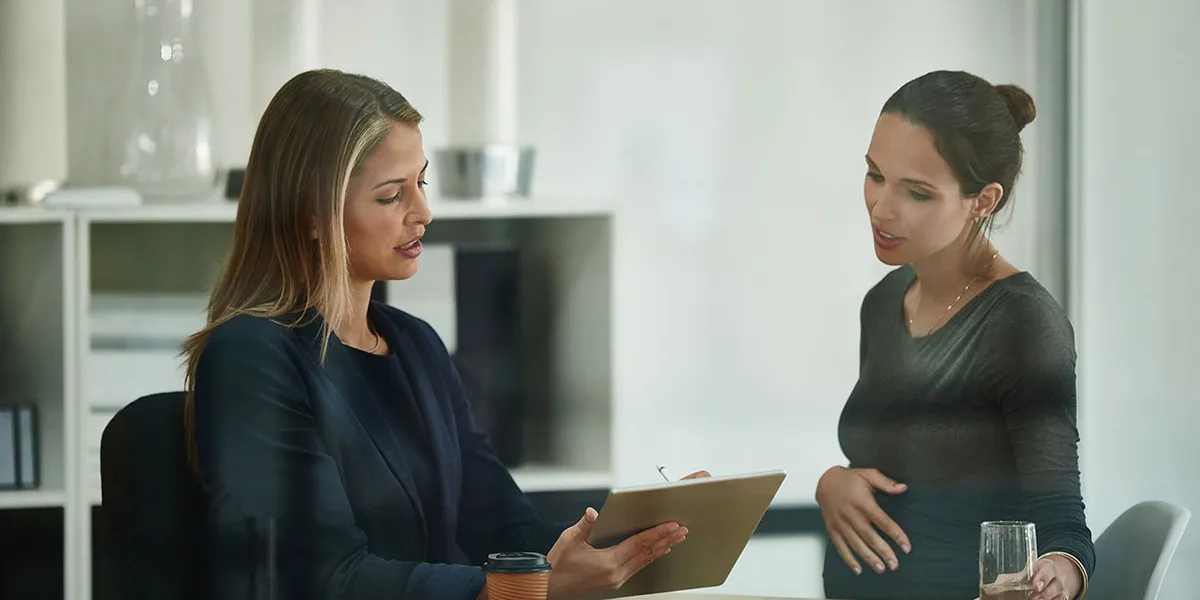 Vorgesetzte bespricht mit einer schwangeren Mitarbeiterin das Mutterschutzgesetz.