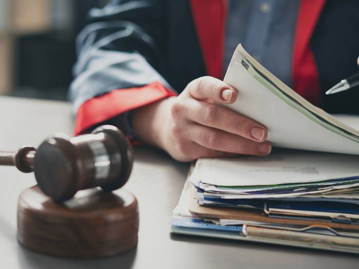 Person mit Richterhammer prüft Dokumente zu gesetzlichen Regelungen im Arbeitsrecht und Mindestlohn.