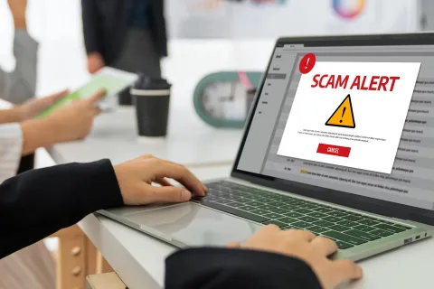 Ein Mitarbeiter wird durch eine Meldung auf seinem Laptop über einen Hackerangriff informiert.