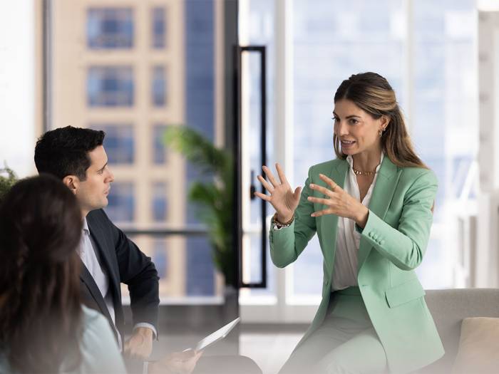 Führungskraft spricht engagiert vor einem Team und erläutert Inhalte in einem Meetingraum.