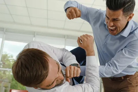 Ein Mitarbeiter übt körperliche Gewalt am Arbeitsplatz an seinem Kollegen aus. © Adobe Stock, New Africa