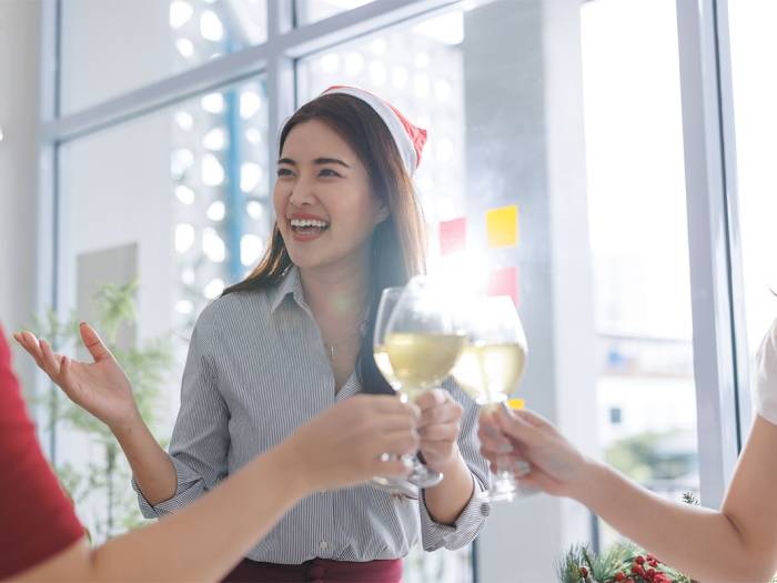 Drei Mitarbeitende stoßen auf der Weihnachtsfeier im Betrieb an.