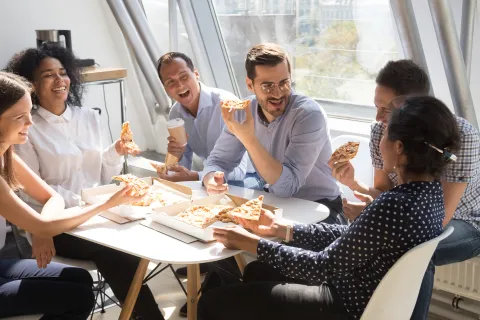 Mitarbeiter essen in der Pause Pizza und müssen mit einem Mitagstief aufgrund des fettigen Essens rechnen. © Shutterstock, fizkes